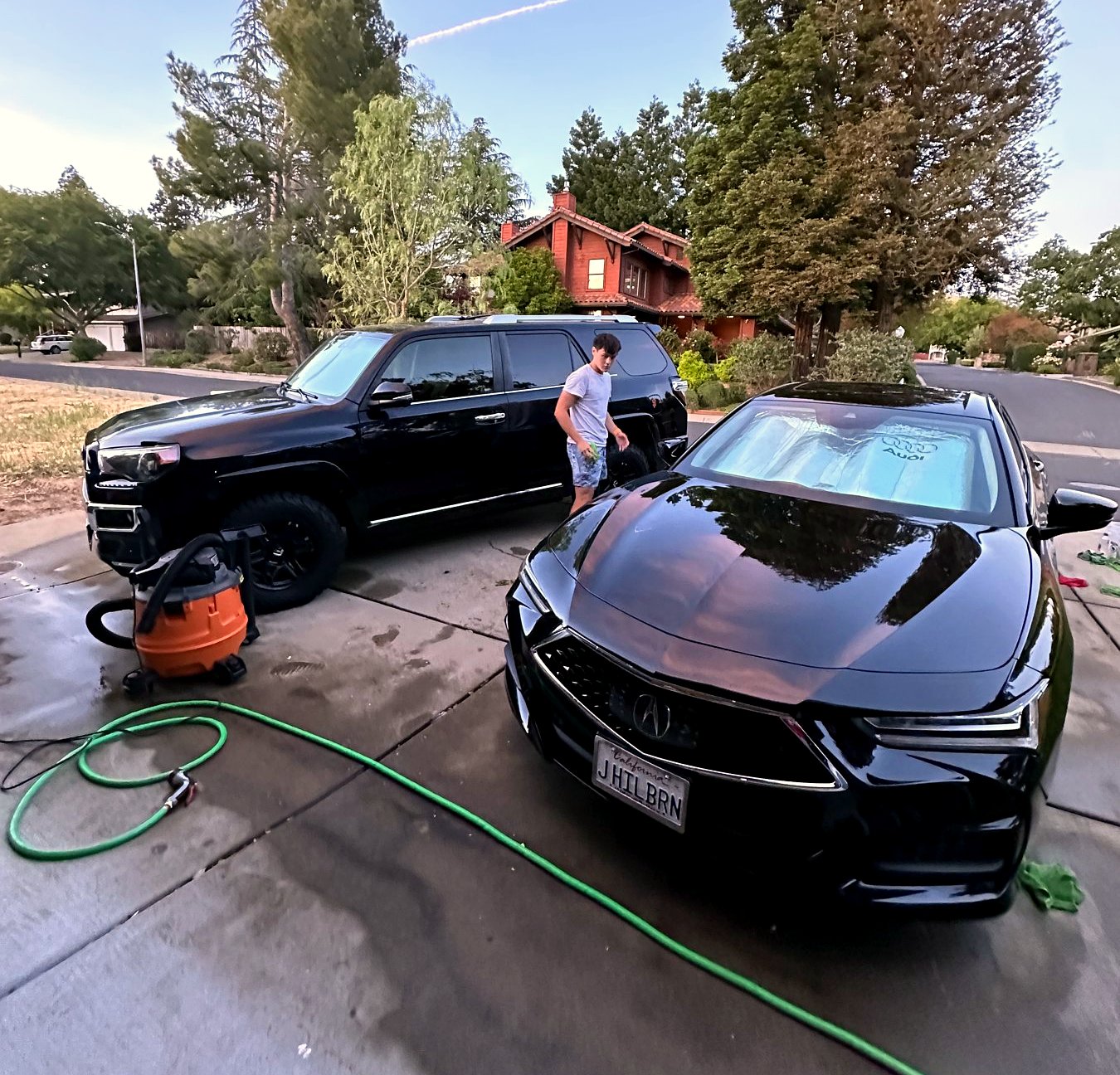 Maxim detailing two cars in a driveway at golden hour